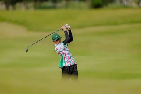 Junior golfer swinging on the fairway