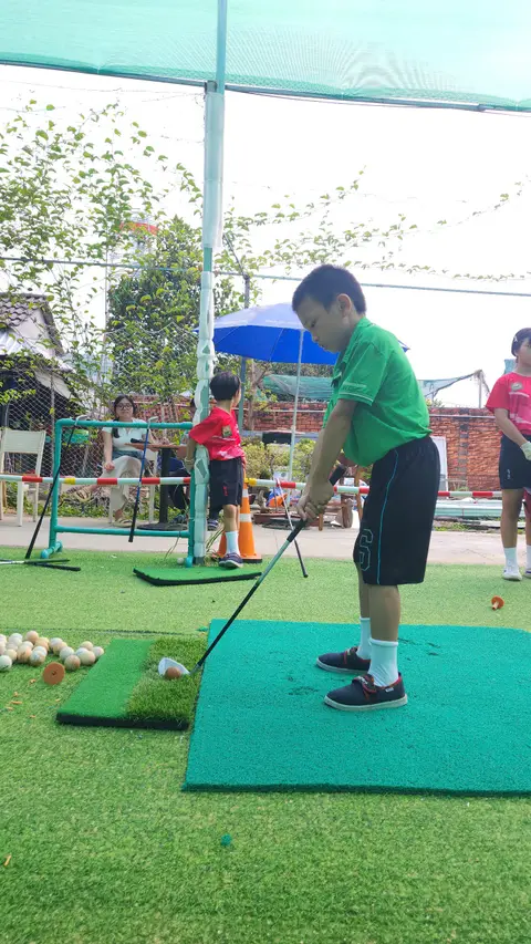 Bé tập đánh golf tại khu tập